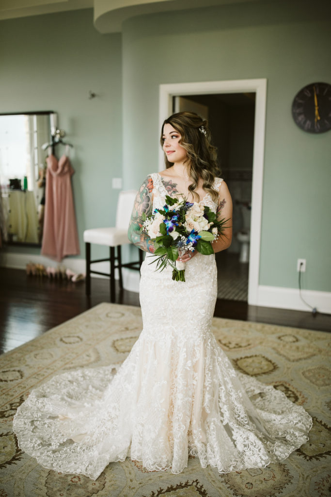Bride in wedding gown poses inside with bouquet