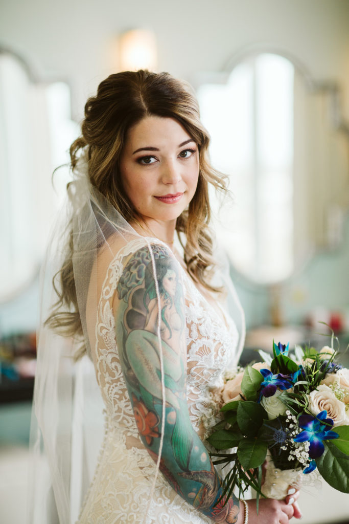 bride with tattoos holding colorful bouquet
